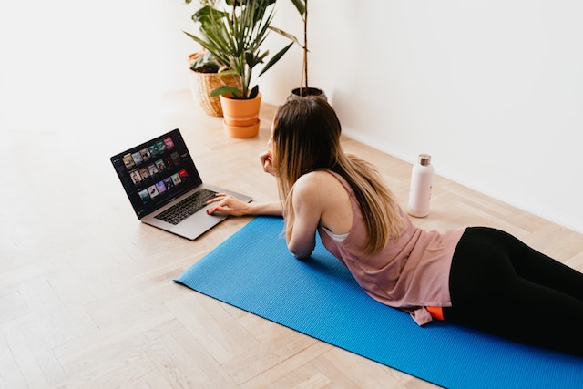 Woman Laying On Yoga Mat With Computer