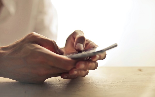 Person Holding Phone On Table