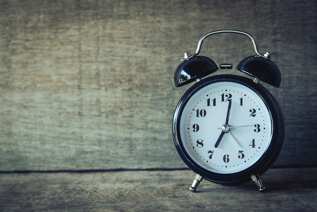 Black analog clock on wood background