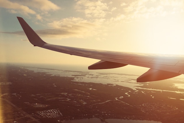 Airplane wing over water with sun