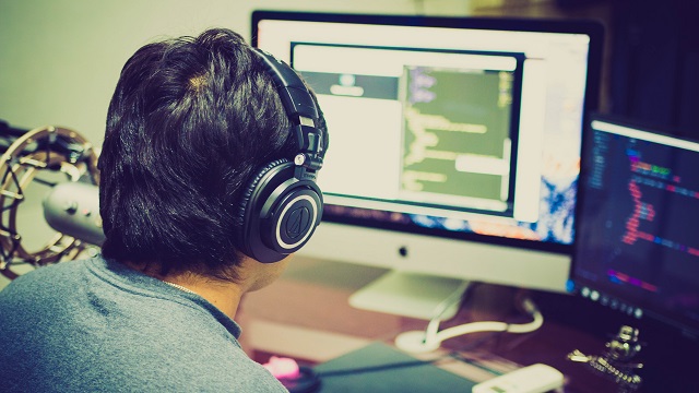 Man Wearing Headphones While Viewing Computer