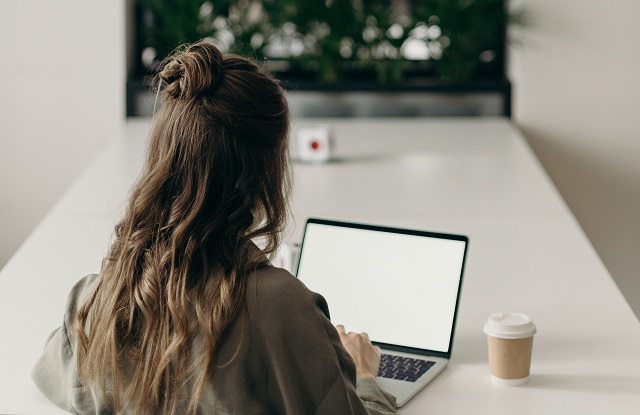 Woman using laptop with coffee cup nearby