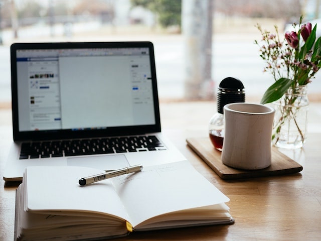 Notebook open on desk in front of computer