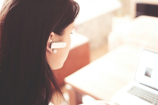 Woman using Bluetooth earpiece to make phone call