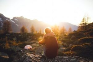 Woman sitting in mountains looking at sunset