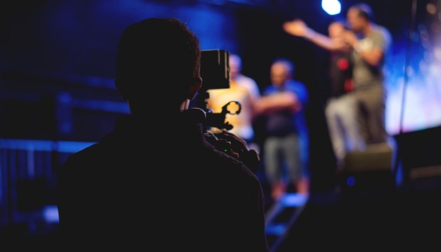 Person filming group on a stage