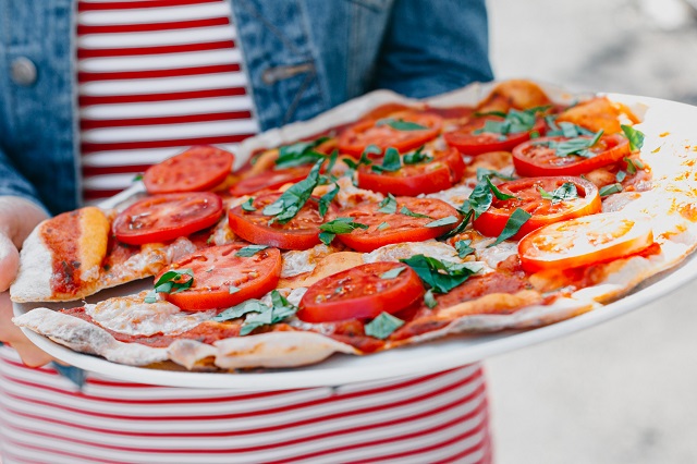 Pizza being served on a white platter