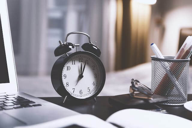 Clock on desk next next to laptop