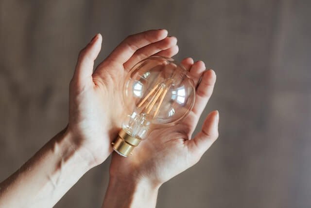 Light bulb resting in a person’s hands. 