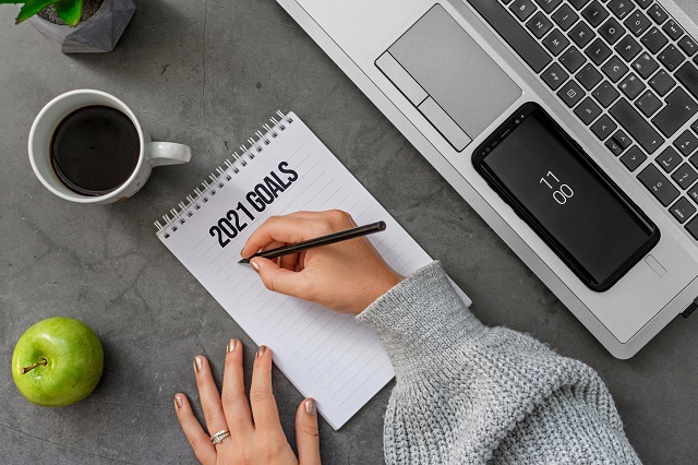 Person writing their business goals on a notepad