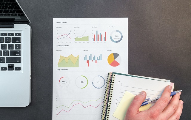 Hand resting on a notepad with printed graphs underneath