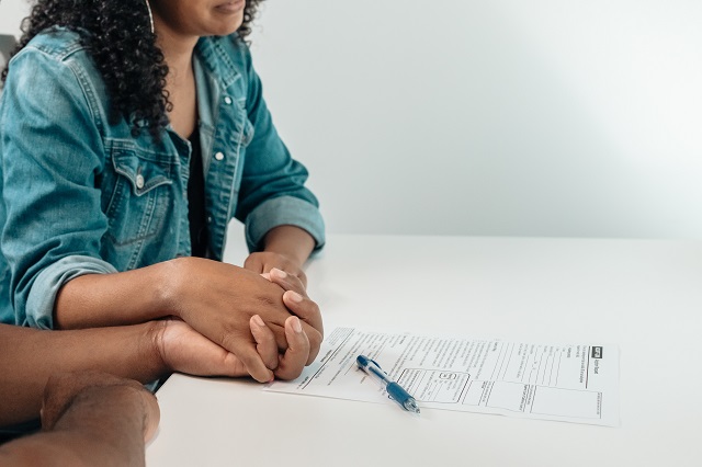 Couple holding hands with a contract and pen on table in front of them