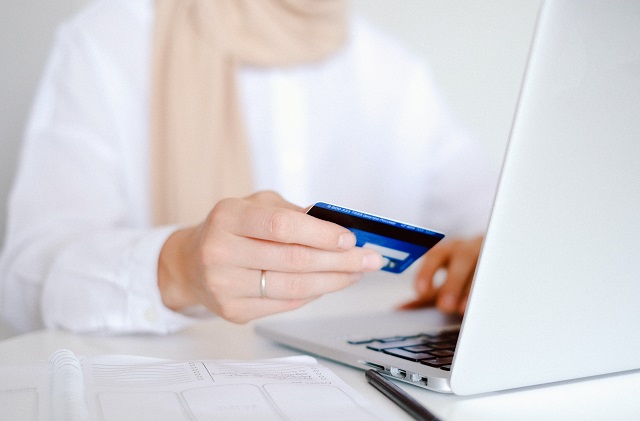 Person holding credit card while viewing laptop