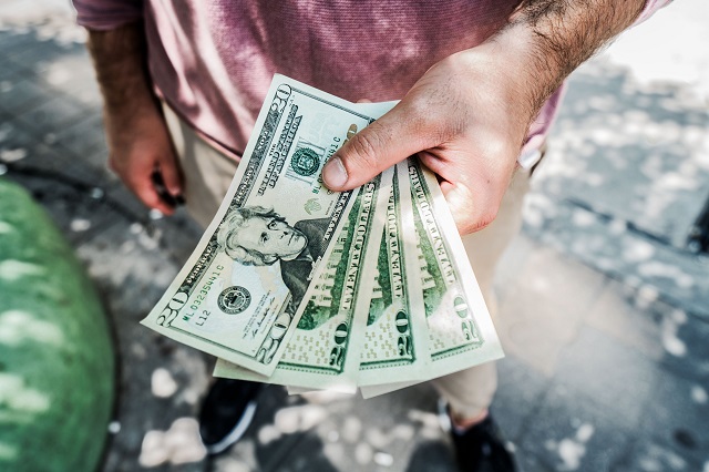 Man holding a stack of twenty-dollar bills