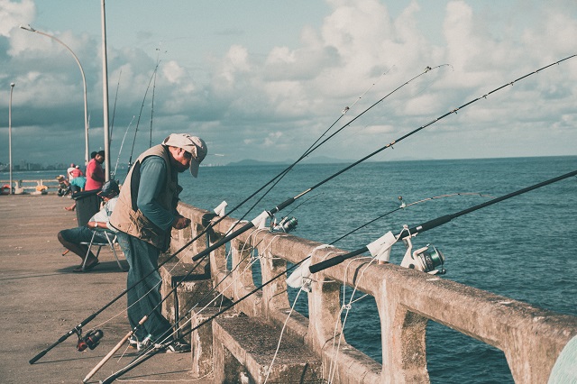 Multiple fishing poles leaning on pier railing