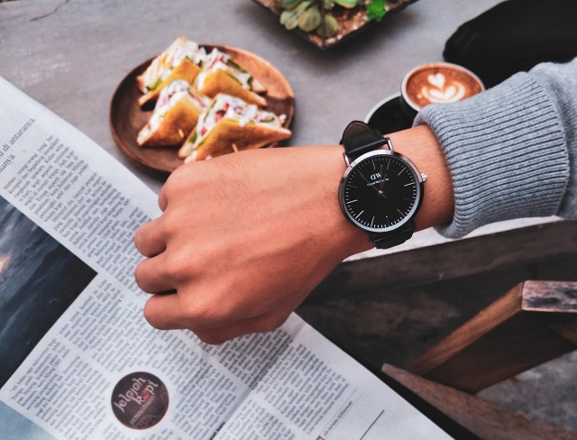 Person reading paper and checking wristwatch