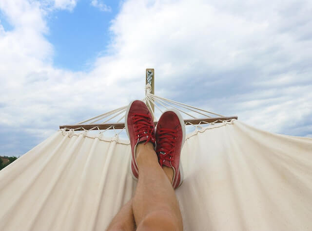 Close-up of person with feet up in a hammock outdoors.