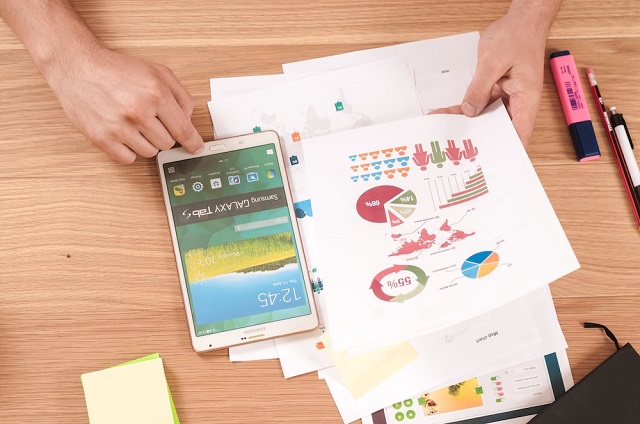 Close-up of person looking at charts next to smartphone