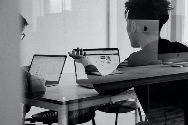 Black and white photo of man looking at laptop screen