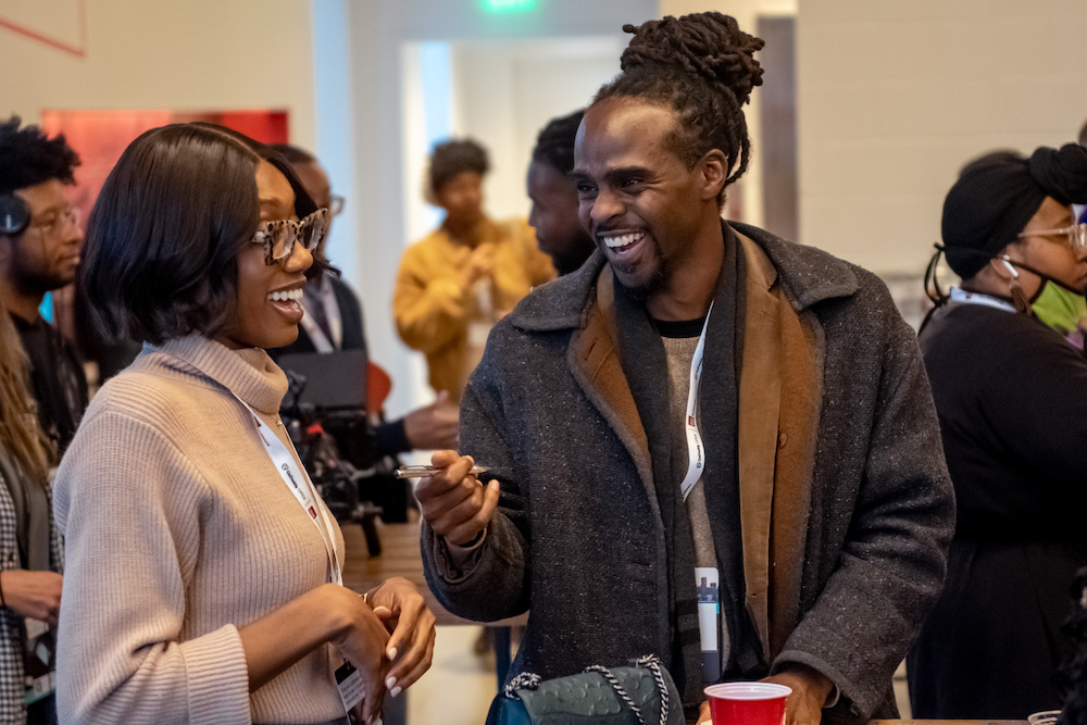 Two entrepreneurs laughing together in a crowded room