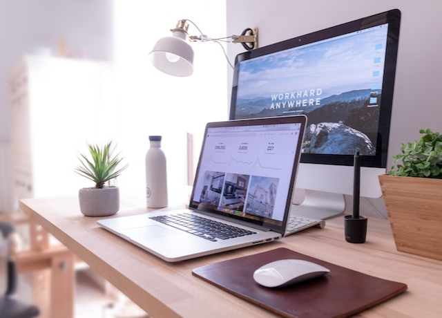 Multiple computers on a light-toned wood desk