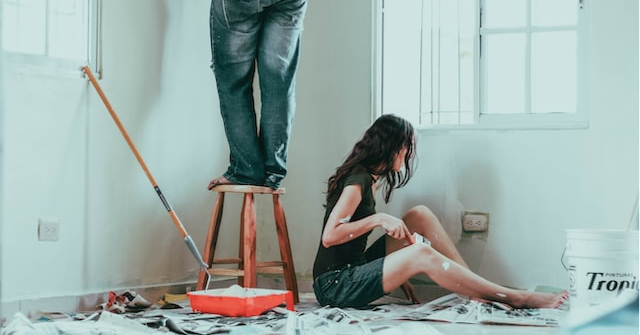 Two people painting the walls of a house