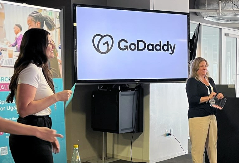 Carissa Haydon, GoDaddy’s director of business development presenting in front of a TV with GoDaddy's logo