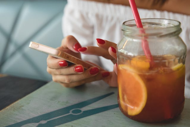 Generate Reviews Customer Leaving Review on Phone with Glass of Iced Tea
