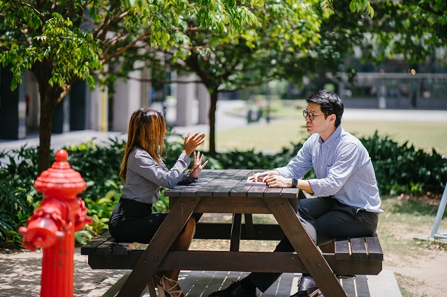 Two People Having A Discussion At A Picnic Bench