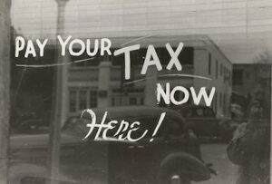 Pay Your Tax Now Here Written on Storefront Window