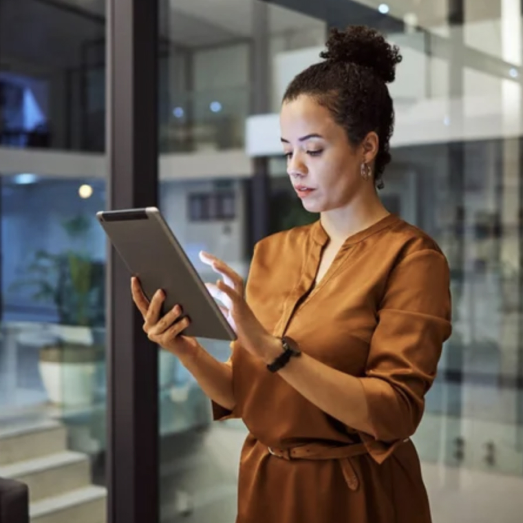 Woman in brown dress using tablet in modern office