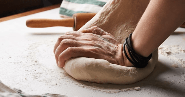 Person kneading bread dough on a floured surface