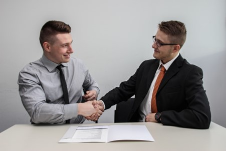 2 gentlemen shaking hands after signing a contract at a business meeting