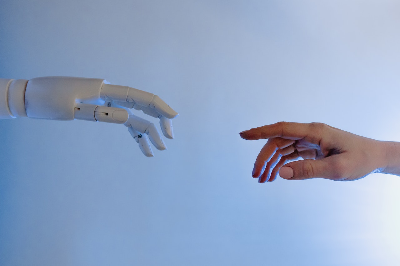 Robot's hand and a human hand reaching to touch each other.