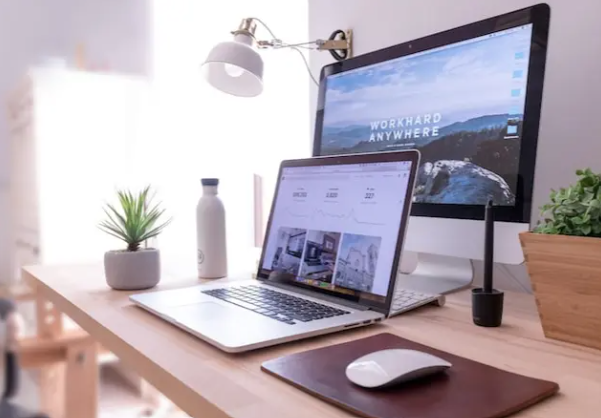 Multiple computers on a light-toned wood desk