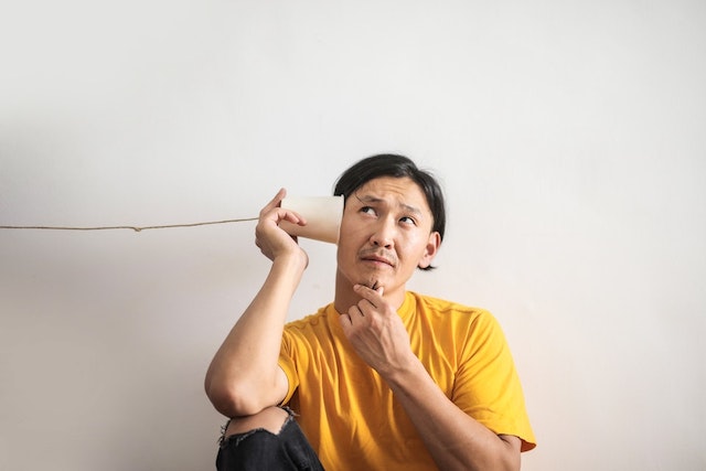 Guy sitting down with a string phone on left ear