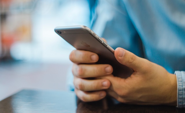 Man in blue shirt holding a smartphone