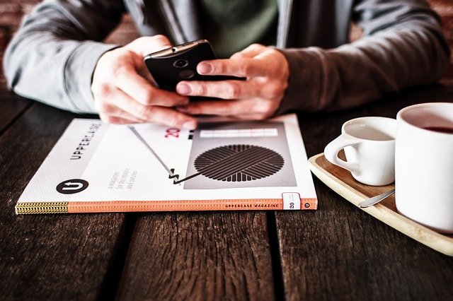 Man sitting at a wooden table with his smartphone