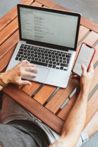 Person managing email on his phone and laptop]