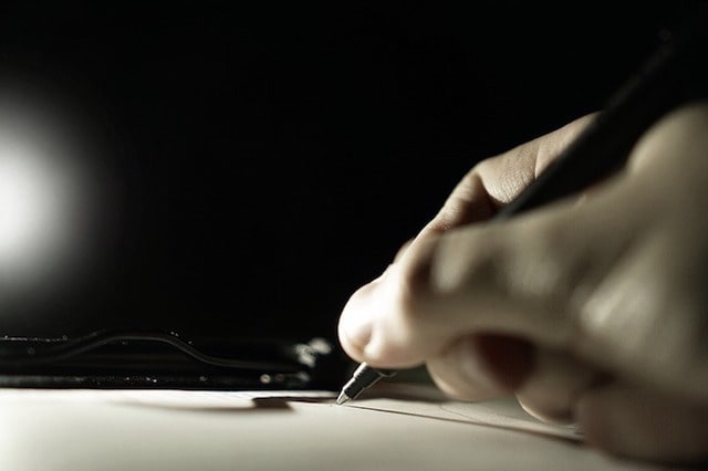 Photo of Person Signing a Clipboard