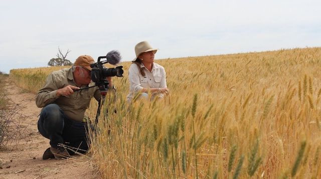 Two people from nviro media shooting video in a field