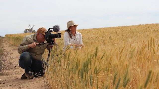 Two people from nviro media shooting video in a field