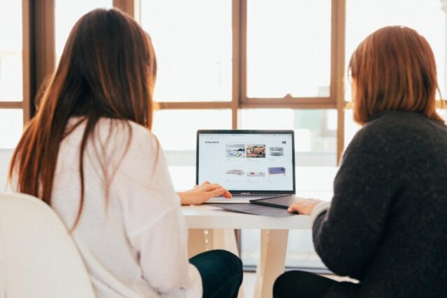 Two women looking at one laptop