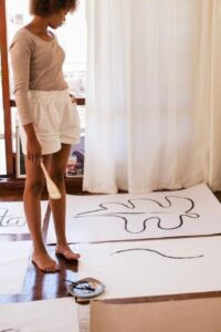 Woman Creating Art on Large White Sheets of Paper