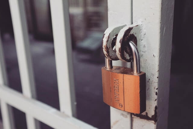 Close-up of a padlock on a white iron gate