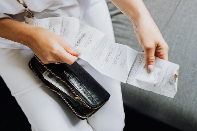 Close-up of person looking at a receipt with open wallet in lap