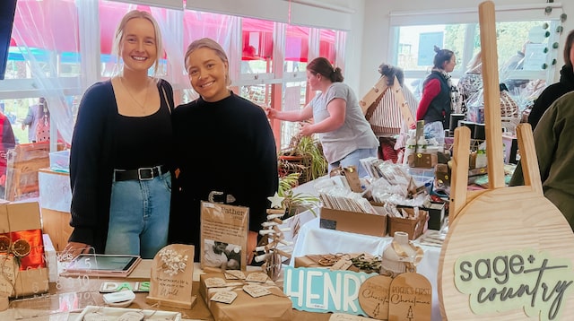 Ellie and Elyssa standing at their Sage and Country booth