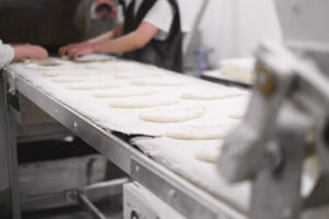 People preparing dough on conveyor belt for production