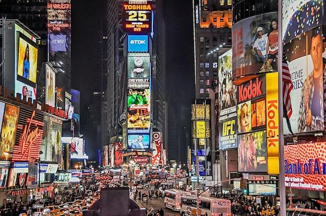 Times Square at night with various lights illuminating different brands.