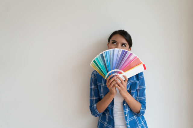 Woman holding a color swatch book in front of her face